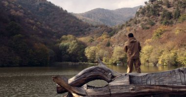 Dağların ortasında gölde balıkçılık yapan sporcu balıkçı doğa fotoğrafı. Red Epic Dragon 'da çekilmiş. Sinematik fotoğraf.