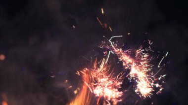 Şenlik ateşi kıvılcımlarının Macro fotoğrafı. Alevler patlar, patlamalar. Patlama mikro parlaklığı. Mini Havai fişekler. Kırmızı kamerada çekim hala siyah arkaplanda. Güzel sızıntılar kıvılcım posteri, afiş, duvar kağıdı, arkaplan, doku.