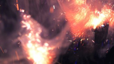 Şenlik ateşi kıvılcımlarının Macro fotoğrafı. Alevler patlar, patlamalar. Patlama mikro parlaklığı. Mini Havai fişekler. Kırmızı kamerada çekim hala siyah arkaplanda. Güzel sızıntılar kıvılcım posteri, afiş, duvar kağıdı, arkaplan, doku.
