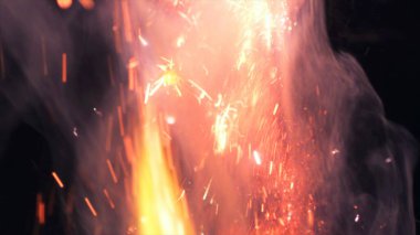 Şenlik ateşi kıvılcımlarının Macro fotoğrafı. Alevler patlar, patlamalar. Patlama mikro parlaklığı. Mini Havai fişekler. Kırmızı kamerada çekim hala siyah arkaplanda. Güzel sızıntılar kıvılcım posteri, afiş, duvar kağıdı, arkaplan, doku.