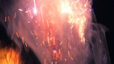 Şenlik ateşi kıvılcımlarının Macro fotoğrafı. Alevler patlar, patlamalar. Patlama mikro parlaklığı. Mini Havai fişekler. Kırmızı kamerada çekim hala siyah arkaplanda. Güzel sızıntılar kıvılcım posteri, afiş, duvar kağıdı, arkaplan, doku.