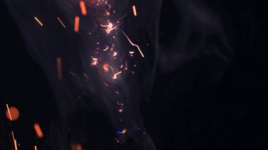 Şenlik ateşi kıvılcımlarının Macro fotoğrafı. Alevler patlar, patlamalar. Patlama mikro parlaklığı. Mini Havai fişekler. Kırmızı kamerada çekim hala siyah arkaplanda. Güzel sızıntılar kıvılcım posteri, afiş, duvar kağıdı, arkaplan, doku.