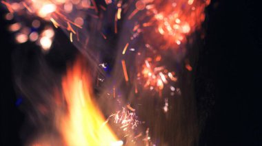 Şenlik ateşi kıvılcımlarının Macro fotoğrafı. Alevler patlar, patlamalar. Patlama mikro parlaklığı. Mini Havai fişekler. Kırmızı kamerada çekim hala siyah arkaplanda. Güzel sızıntılar kıvılcım posteri, afiş, duvar kağıdı, arkaplan, doku.