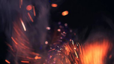 Şenlik ateşi kıvılcımlarının Macro fotoğrafı. Alevler patlar, patlamalar. Patlama mikro parlaklığı. Mini Havai fişekler. Kırmızı kamerada çekim hala siyah arkaplanda. Güzel sızıntılar kıvılcım posteri, afiş, duvar kağıdı, arkaplan, doku.