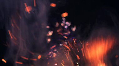 Şenlik ateşi kıvılcımlarının Macro fotoğrafı. Alevler patlar, patlamalar. Patlama mikro parlaklığı. Mini Havai fişekler. Kırmızı kamerada çekim hala siyah arkaplanda. Güzel sızıntılar kıvılcım posteri, afiş, duvar kağıdı, arkaplan, doku.