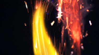 Şenlik ateşi kıvılcımlarının Macro fotoğrafı. Alevler patlar, patlamalar. Patlama mikro parlaklığı. Mini Havai fişekler. Kırmızı kamerada çekim hala siyah arkaplanda. Güzel sızıntılar kıvılcım saçar.