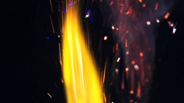 Şenlik ateşi kıvılcımlarının Macro fotoğrafı. Alevler patlar, patlamalar. Patlama mikro parlaklığı. Mini Havai fişekler. Kırmızı kamerada çekim hala siyah arkaplanda. Güzel sızıntılar kıvılcım saçar.