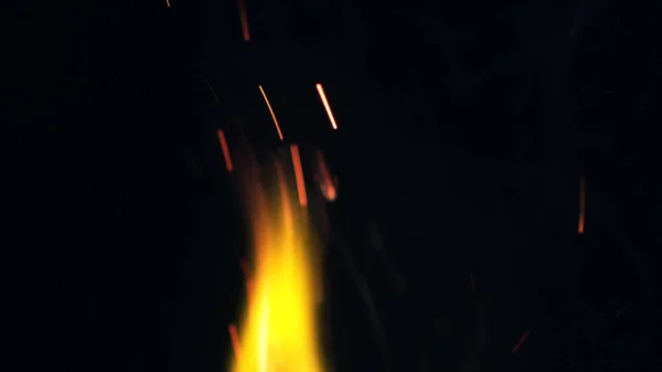 Macro photo of Bonfire sparks. Fire Flames bursts, blasts. Explosion micro sparkles. Mini Fireworks. Shooting on Red camera still on black background. Beautiful leaks overlay spark.