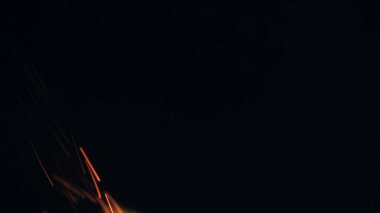 Şenlik ateşi kıvılcımlarının Macro fotoğrafı. Alevler patlar, patlamalar. Patlama mikro parlaklığı. Mini Havai fişekler. Kırmızı kamerada çekim hala siyah arkaplanda. Kıvılcım posteri, afiş, duvar kağıdı, doku.
