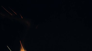 Şenlik ateşi kıvılcımlarının Macro fotoğrafı. Alevler patlar, patlamalar. Patlama mikro parlaklığı. Mini Havai fişekler. Kırmızı kamerada çekim hala siyah arkaplanda. Kıvılcım posteri, afiş, duvar kağıdı, doku.