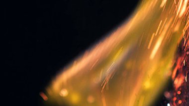 Şenlik ateşi kıvılcımlarının Macro fotoğrafı. Alevler patlar, patlamalar. Patlama mikro parlaklığı. Mini Havai fişekler. Kırmızı kamerada çekim hala siyah arkaplanda. Güzel sızıntılar kıvılcım posteri, afiş, duvar kağıdı, arkaplan, doku.