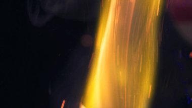 Şenlik ateşi kıvılcımlarının Macro fotoğrafı. Alevler patlar, patlamalar. Patlama mikro parlaklığı. Mini Havai fişekler. Kırmızı kamerada çekim hala siyah arkaplanda. Güzel sızıntılar kıvılcım posteri, afiş, duvar kağıdı, arkaplan, doku.