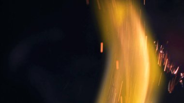 Şenlik ateşi kıvılcımlarının Macro fotoğrafı. Alevler patlar, patlamalar. Patlama mikro parlaklığı. Mini Havai fişekler. Kırmızı kamerada çekim hala siyah arkaplanda. Güzel sızıntılar kıvılcım posteri, afiş, duvar kağıdı, arkaplan, doku.