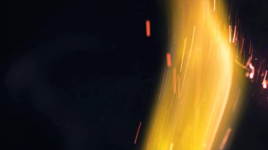 Şenlik ateşi kıvılcımlarının Macro fotoğrafı. Alevler patlar, patlamalar. Patlama mikro parlaklığı. Mini Havai fişekler. Kırmızı kamerada çekim hala siyah arkaplanda. Güzel sızıntılar kıvılcım posteri, afiş, duvar kağıdı, arkaplan, doku.