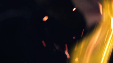 Şenlik ateşi kıvılcımlarının Macro fotoğrafı. Alevler patlar, patlamalar. Patlama mikro parlaklığı. Mini Havai fişekler. Kırmızı kamerada çekim hala siyah arkaplanda. Güzel sızıntılar kıvılcım posteri, afiş, duvar kağıdı, arkaplan, doku.