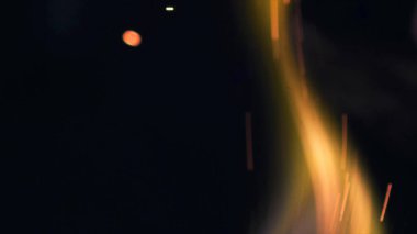 Şenlik ateşi kıvılcımlarının Macro fotoğrafı. Alevler patlar, patlamalar. Patlama mikro parlaklığı. Mini Havai fişekler. Kırmızı kamerada çekim hala siyah arkaplanda. Güzel sızıntılar kıvılcım posteri, afiş, duvar kağıdı, arkaplan, doku.