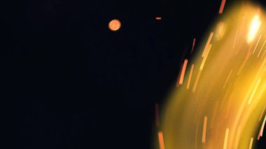 Şenlik ateşi kıvılcımlarının Macro fotoğrafı. Alevler patlar, patlamalar. Patlama mikro parlaklığı. Mini Havai fişekler. Kırmızı kamerada çekim hala siyah arkaplanda. Güzel sızıntılar kıvılcım posteri, afiş, duvar kağıdı, arkaplan, doku.