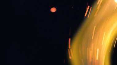 Şenlik ateşi kıvılcımlarının Macro fotoğrafı. Alevler patlar, patlamalar. Patlama mikro parlaklığı. Mini Havai fişekler. Kırmızı kamerada çekim hala siyah arkaplanda. Güzel sızıntılar kıvılcım posteri, afiş, duvar kağıdı, arkaplan, doku.