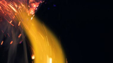 Şenlik ateşi kıvılcımlarının Macro fotoğrafı. Alevler patlar, patlamalar. Patlama mikro parlaklığı. Mini Havai fişekler. Kırmızı kamerada çekim hala siyah arkaplanda. Güzel sızıntılar kıvılcım posteri, afiş, duvar kağıdı, arkaplan, doku.