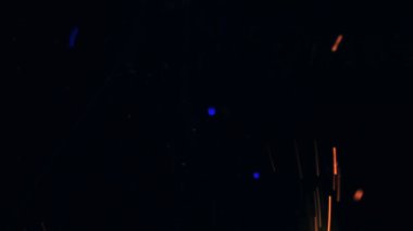 Şenlik ateşi kıvılcımlarının Macro fotoğrafı. Alevler patlar, patlamalar. Patlama mikro parlaklığı. Mini Havai fişekler. Kırmızı kamerada çekim hala siyah arkaplanda. Güzel sızıntılar kıvılcım posteri, afiş, duvar kağıdı, arkaplan, doku.