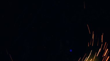Şenlik ateşi kıvılcımlarının Macro fotoğrafı. Alevler patlar, patlamalar. Patlama mikro parlaklığı. Mini Havai fişekler. Kırmızı kamerada çekim hala siyah arkaplanda. Güzel sızıntılar kıvılcım posteri, afiş, duvar kağıdı, arkaplan, doku.