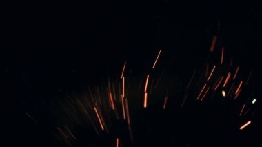 Şenlik ateşi kıvılcımlarının Macro fotoğrafı. Alevler patlar, patlamalar. Patlama mikro parlaklığı. Mini Havai fişekler. Kırmızı kamerada çekim hala siyah arkaplanda. Güzel sızıntılar kıvılcım posteri, afiş, duvar kağıdı, arkaplan, doku.