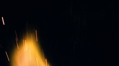 Şenlik ateşi kıvılcımlarının Macro fotoğrafı. Alevler patlar, patlamalar. Patlama mikro parlaklığı. Mini Havai fişekler. Kırmızı kamerada çekim hala siyah arkaplanda. Güzel sızıntılar kıvılcım posteri, afiş, duvar kağıdı, arkaplan, doku.