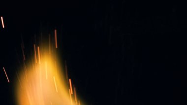 Şenlik ateşi kıvılcımlarının Macro fotoğrafı. Alevler patlar, patlamalar. Patlama mikro parlaklığı. Mini Havai fişekler. Kırmızı kamerada çekim hala siyah arkaplanda. Güzel sızıntılar kıvılcım posteri, afiş, duvar kağıdı, arkaplan, doku.