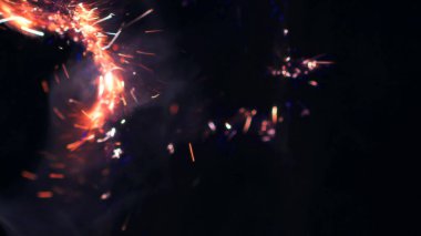 Şenlik ateşi kıvılcımlarının Macro fotoğrafı. Alevler patlar, patlamalar. Patlama mikro parlaklığı. Mini Havai fişekler. Kırmızı kamerada çekim hala siyah arkaplanda. Güzel sızıntılar kıvılcım posteri, afiş, duvar kağıdı, arkaplan, doku.