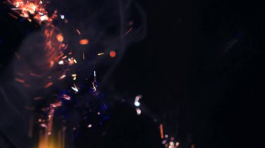 Şenlik ateşi kıvılcımlarının Macro fotoğrafı. Alevler patlar, patlamalar. Patlama mikro parlaklığı. Mini Havai fişekler. Kırmızı kamerada çekim hala siyah arkaplanda. Güzel sızıntılar kıvılcım posteri, afiş, duvar kağıdı, arkaplan, doku.