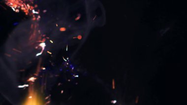 Şenlik ateşi kıvılcımlarının Macro fotoğrafı. Alevler patlar, patlamalar. Patlama mikro parlaklığı. Mini Havai fişekler. Kırmızı kamerada çekim hala siyah arkaplanda. Güzel sızıntılar kıvılcım posteri, afiş, duvar kağıdı, arkaplan, doku.