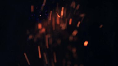 Şenlik ateşi kıvılcımlarının Macro fotoğrafı. Alevler patlar, patlamalar. Patlama mikro parlaklığı. Mini Havai fişekler. Kırmızı kamerada çekim hala siyah arkaplanda. Güzel sızıntılar kıvılcım posteri, afiş, duvar kağıdı, arkaplan, doku.