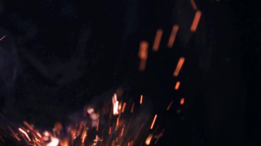 Şenlik ateşi kıvılcımlarının Macro fotoğrafı. Alevler patlar, patlamalar. Patlama mikro parlaklığı. Mini Havai fişekler. Kırmızı kamerada çekim hala siyah arkaplanda. Güzel sızıntılar kıvılcım posteri, afiş, duvar kağıdı, arkaplan, doku.