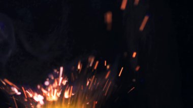 Şenlik ateşi kıvılcımlarının Macro fotoğrafı. Alevler patlar, patlamalar. Patlama mikro parlaklığı. Mini Havai fişekler. Kırmızı kamerada çekim hala siyah arkaplanda. Güzel sızıntılar kıvılcım posteri, afiş, duvar kağıdı, arkaplan, doku.