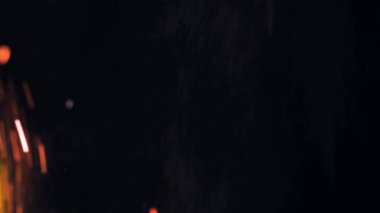 Şenlik ateşi kıvılcımlarının Macro fotoğrafı. Alevler patlar, patlamalar. Patlama mikro parlaklığı. Mini Havai fişekler. Kırmızı kamerada çekim hala siyah arkaplanda. Güzel sızıntılar kıvılcım posteri, afiş, duvar kağıdı, arkaplan, doku.