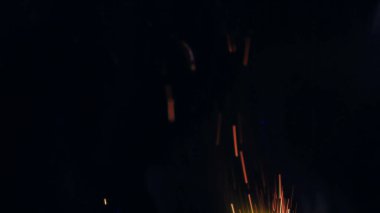 Şenlik ateşi kıvılcımlarının Macro fotoğrafı. Alevler patlar, patlamalar. Patlama mikro parlaklığı. Mini Havai fişekler. Kırmızı kamerada çekim hala siyah arkaplanda. Güzel sızıntılar kıvılcım posteri, afiş, duvar kağıdı, arkaplan, doku.