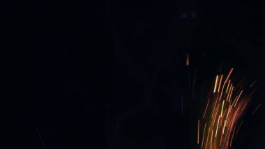 Şenlik ateşi kıvılcımlarının Macro fotoğrafı. Alevler patlar, patlamalar. Patlama mikro parlaklığı. Mini Havai fişekler. Kırmızı kamerada çekim hala siyah arkaplanda. Güzel sızıntılar kıvılcım posteri, afiş, duvar kağıdı, arkaplan, doku.