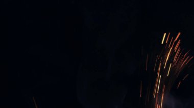 Şenlik ateşi kıvılcımlarının Macro fotoğrafı. Alevler patlar, patlamalar. Patlama mikro parlaklığı. Mini Havai fişekler. Kırmızı kamerada çekim hala siyah arkaplanda. Güzel sızıntılar kıvılcım posteri, afiş, duvar kağıdı, arkaplan, doku.