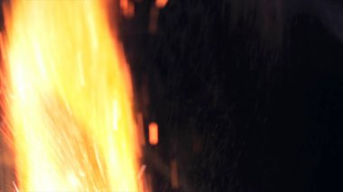 Şenlik ateşi kıvılcımlarının Macro fotoğrafı. Alevler patlar, patlamalar. Patlama mikro parlaklığı. Mini Havai fişekler. Kırmızı kamerada çekim hala siyah arkaplanda. Güzel sızıntılar kıvılcım posteri, afiş, duvar kağıdı, arkaplan, doku.