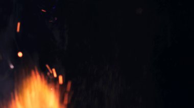 Şenlik ateşi kıvılcımlarının Macro fotoğrafı. Alevler patlar, patlamalar. Patlama mikro parlaklığı. Mini Havai fişekler. Kırmızı kamerada çekim hala siyah arkaplanda. Güzel sızıntılar kıvılcım posteri, afiş, duvar kağıdı, arkaplan, doku.