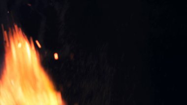 Şenlik ateşi kıvılcımlarının Macro fotoğrafı. Alevler patlar, patlamalar. Patlama mikro parlaklığı. Mini Havai fişekler. Kırmızı kamerada çekim hala siyah arkaplanda. Güzel sızıntılar kıvılcım posteri, afiş, duvar kağıdı, arkaplan, doku.