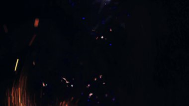 Şenlik ateşi kıvılcımlarının Macro fotoğrafı. Alevler patlar, patlamalar. Patlama mikro parlaklığı. Mini Havai fişekler. Kırmızı kamerada çekim hala siyah arkaplanda. Güzel sızıntılar kıvılcım posteri, afiş, duvar kağıdı, arkaplan, doku.