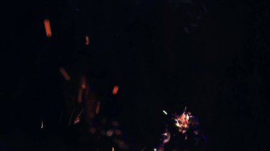 Şenlik ateşi kıvılcımlarının Macro fotoğrafı. Alevler patlar, patlamalar. Patlama mikro parlaklığı. Mini Havai fişekler. Kırmızı kamerada çekim hala siyah arkaplanda. Güzel sızıntılar kıvılcım posteri, afiş, duvar kağıdı, arkaplan, doku.