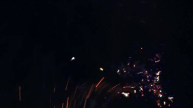 Şenlik ateşi kıvılcımlarının Macro fotoğrafı. Alevler patlar, patlamalar. Patlama mikro parlaklığı. Mini Havai fişekler. Kırmızı kamerada çekim hala siyah arkaplanda. Güzel sızıntılar kıvılcım posteri, afiş, duvar kağıdı, arkaplan, doku.