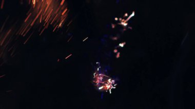 Şenlik ateşi kıvılcımlarının Macro fotoğrafı. Alevler patlar, patlamalar. Patlama mikro parlaklığı. Mini Havai fişekler. Kırmızı kamerada çekim hala siyah arkaplanda. Güzel sızıntılar kıvılcım posteri, afiş, duvar kağıdı, arkaplan, doku.