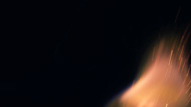 Şenlik ateşi kıvılcımlarının Macro fotoğrafı. Alevler patlar, patlamalar. Patlama mikro parlaklığı. Mini Havai fişekler. Kırmızı kamerada çekim hala siyah arkaplanda. Güzel sızıntılar kıvılcım saçar.