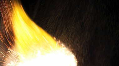 Şenlik ateşi kıvılcımlarının Macro fotoğrafı. Alevler patlar, patlamalar. Patlama mikro parlaklığı. Mini Havai fişekler. Kırmızı kamerada çekim hala siyah arkaplanda. Güzel sızıntılar kıvılcım posteri, afiş, duvar kağıdı, arkaplan, doku.