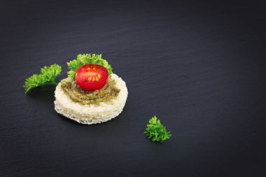 parti ev yapımı kanepe pesto sos siyah arduvaz plaka üzerinde en iyi domates ve maydanoz yaprağı üzerinde parmak gıda