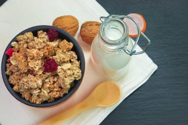 Yemek kahvaltı kavramı organik müsli veya Granola ve siyah arduvaz taş plaka üzerinde peçete ile süt