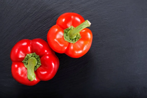 Peperoncino rosso biologico su lastra di pietra di ardesia nera con spazio copia — Foto Stock